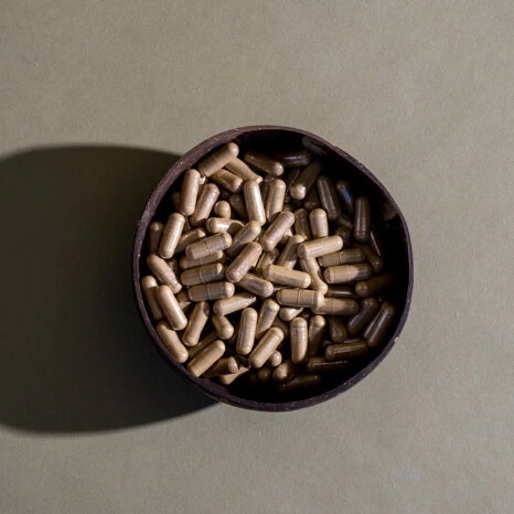 kratom capsules in a brown bowl