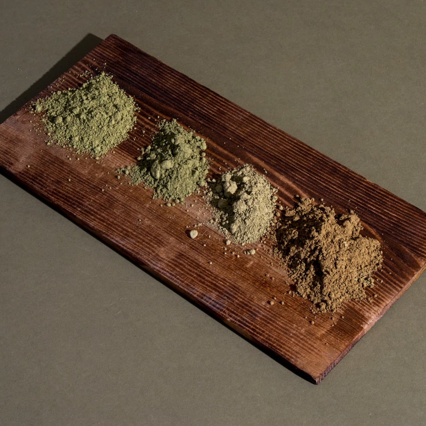 Four piles of kratom powder on a wooden board
