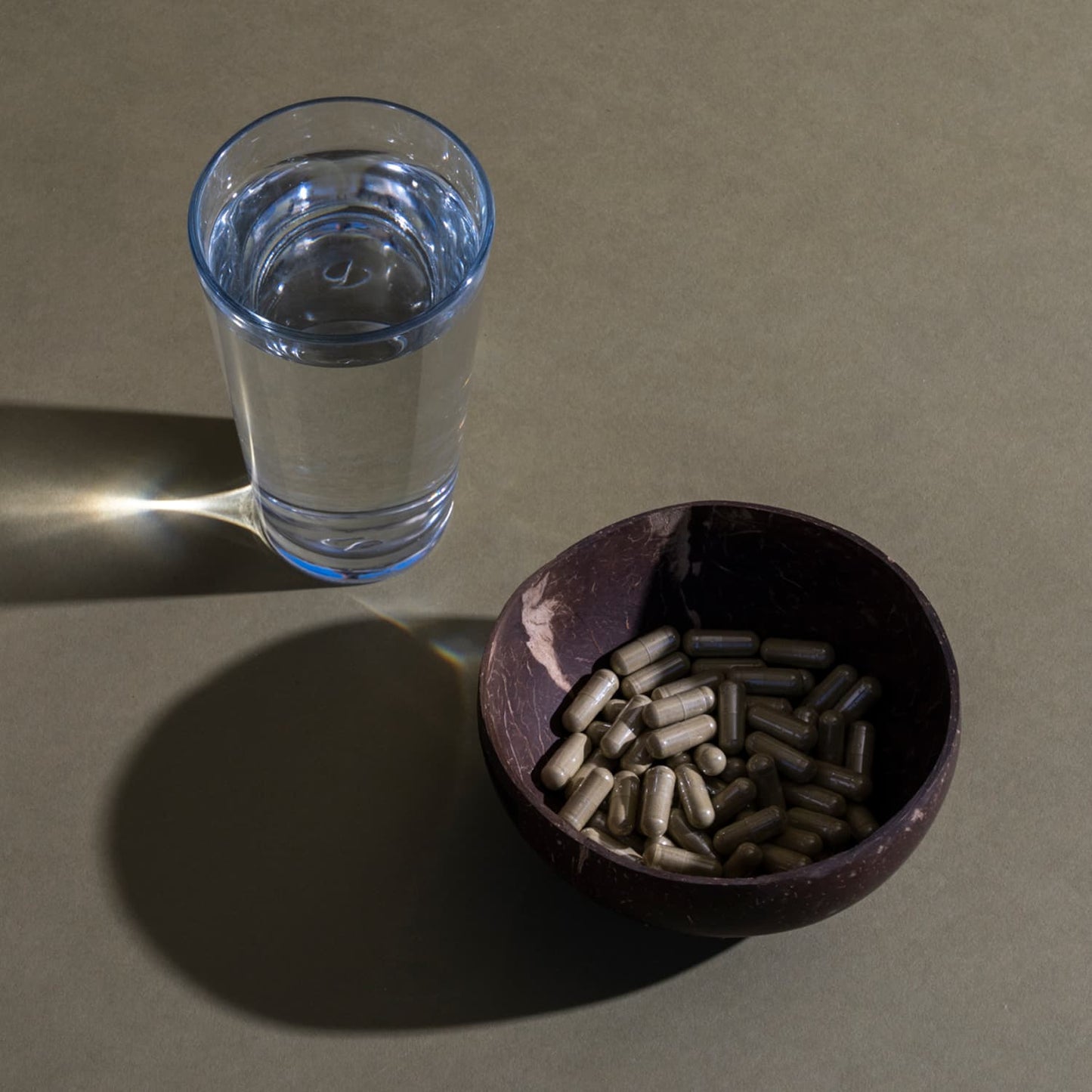 Vietnam Kratom Capsules in a bowl near a glass of water