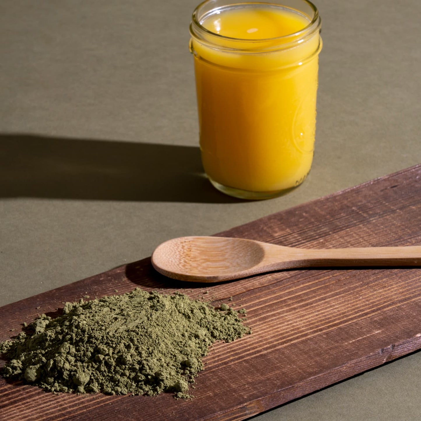 Vietnam Kratom powder on a brown wooden board near a glass of juice