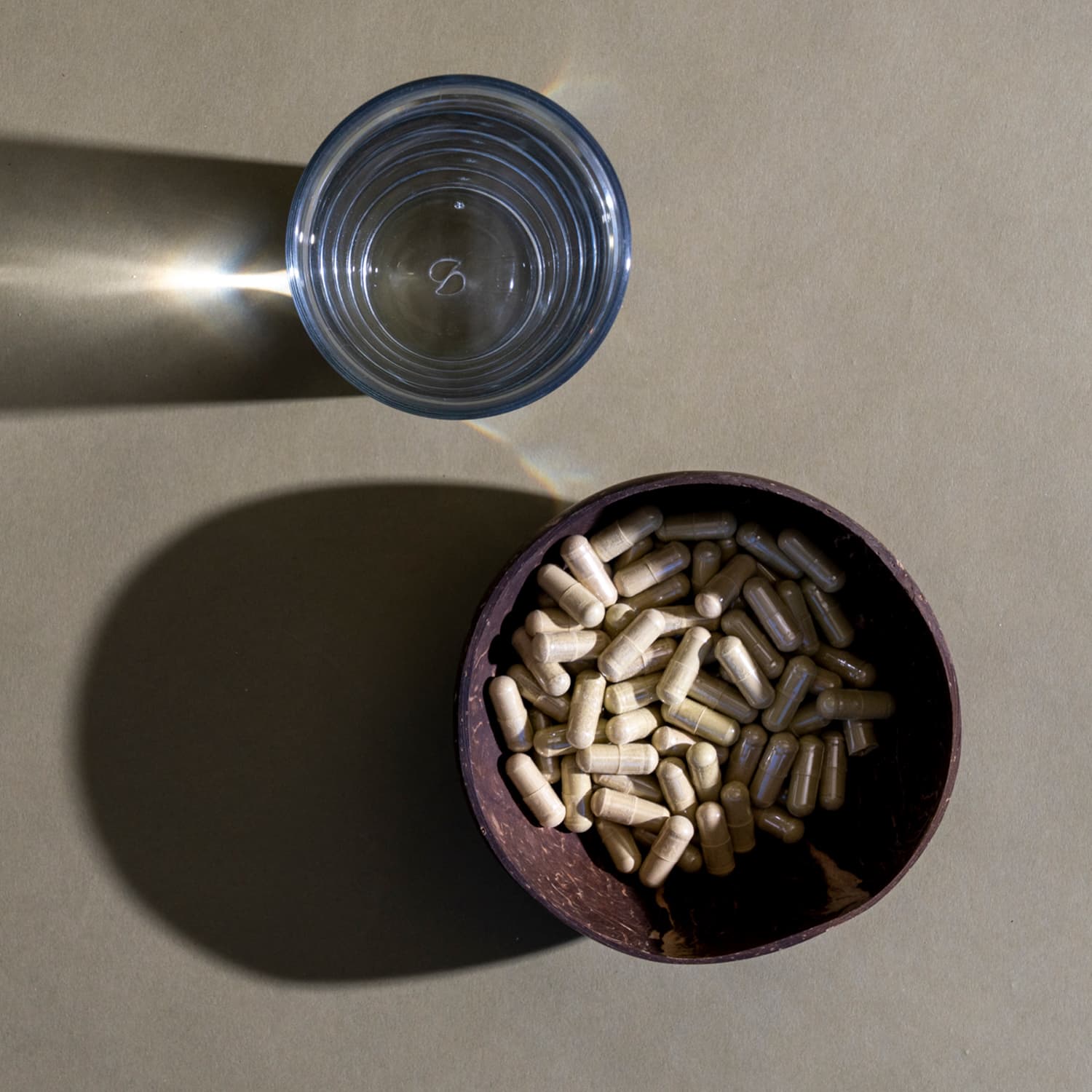 White Vein Kratom Capsules in a bowl near a glass of water