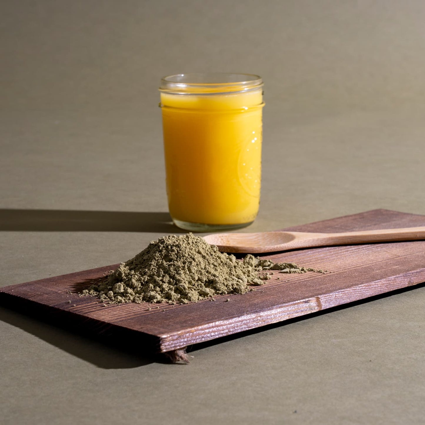 White Vein Kratom on a brown wooden board near a glass of juice